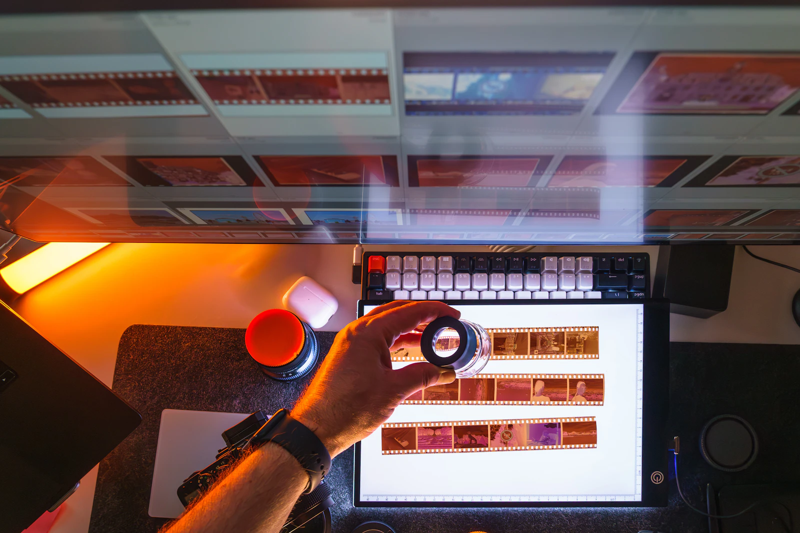 Photographer reviewing film negatives beside a digital editing workspace.