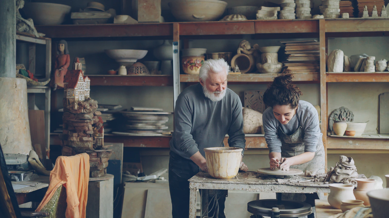 A potter and an apprentice work in a workshop