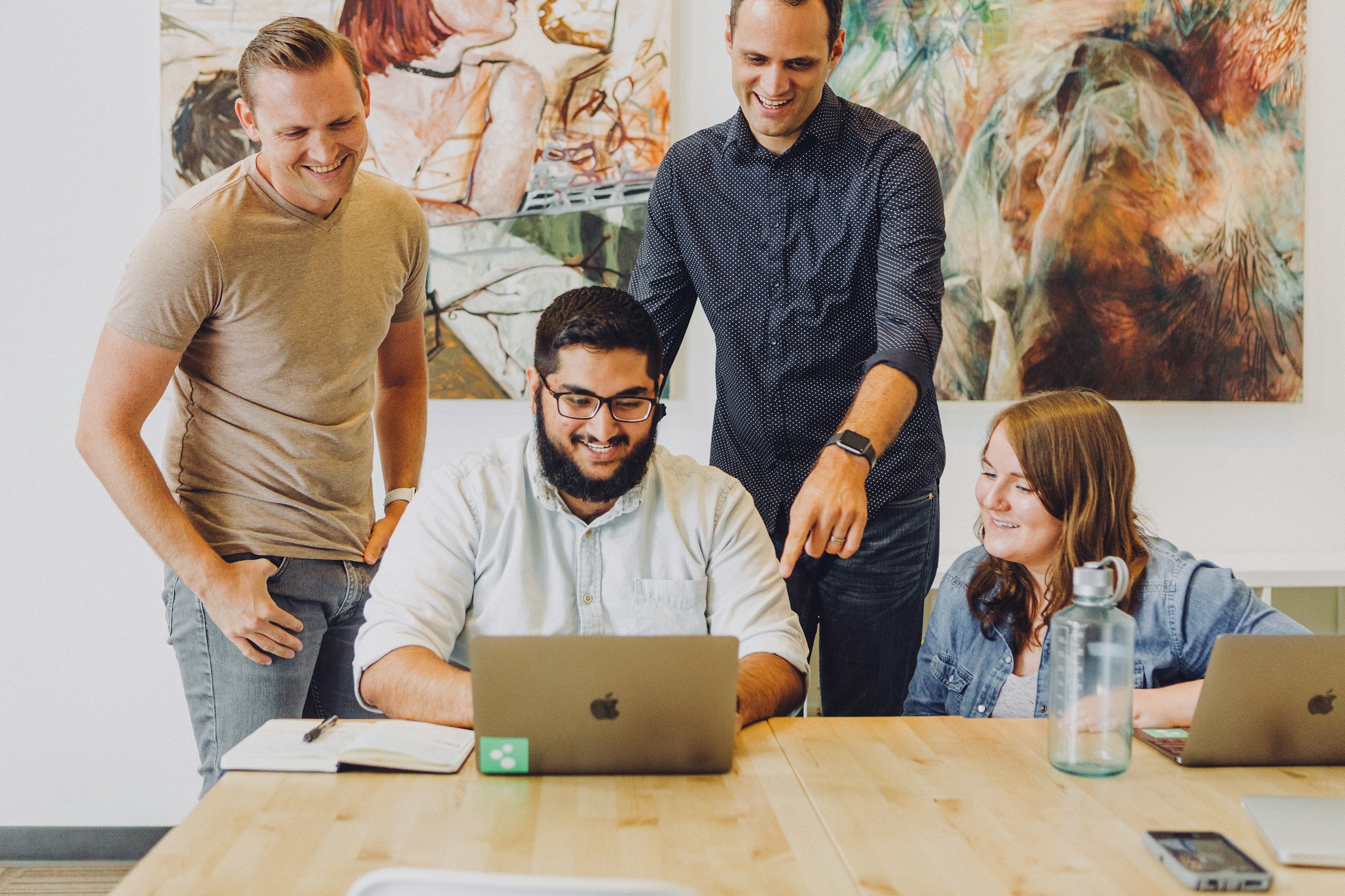 Creative team reviewing design work around a laptop